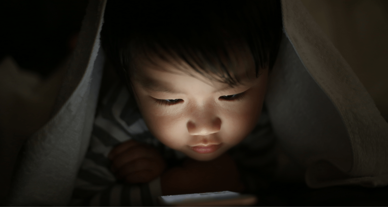 暗い部屋でスマホを見る子供の画像